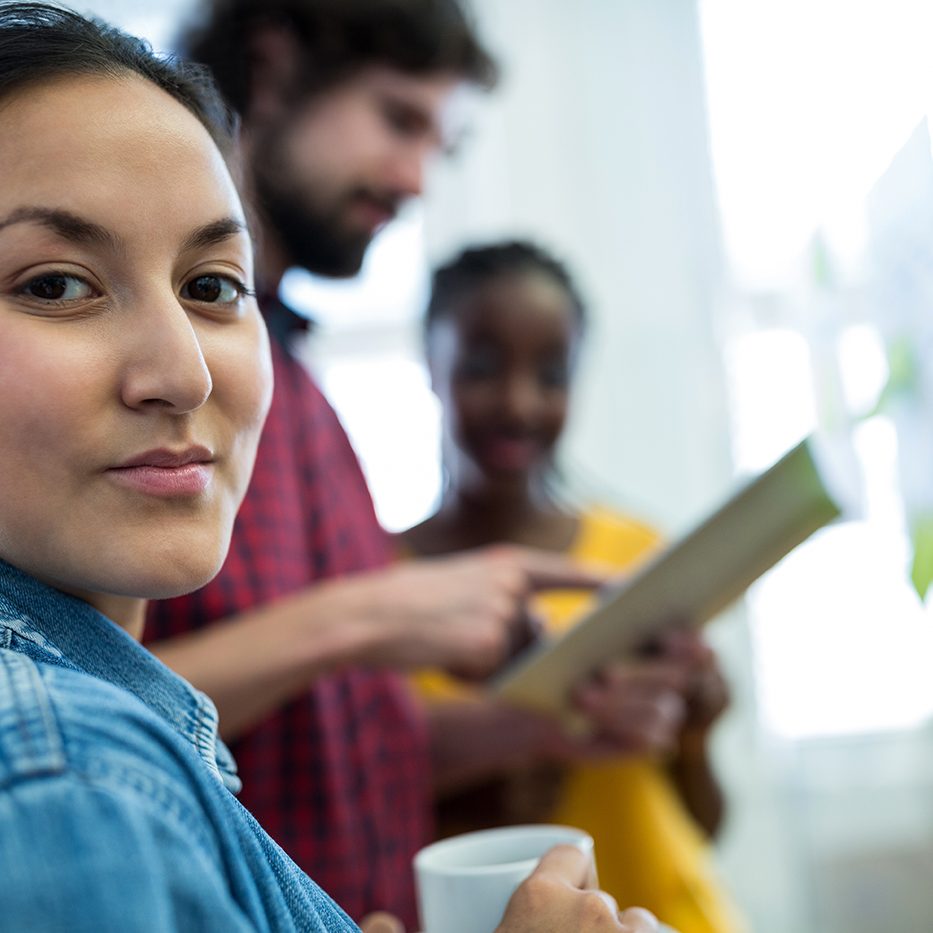 Female graphic designer holding a cup of coffee in office